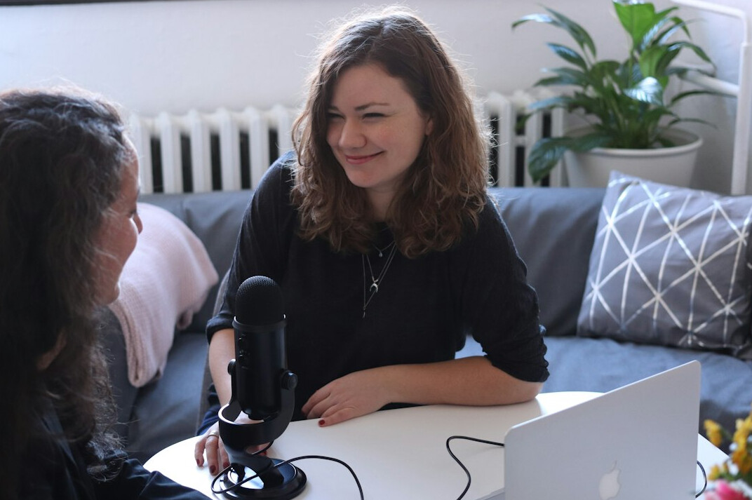 Two Croatian friends smiling while looking at a laptop together at home